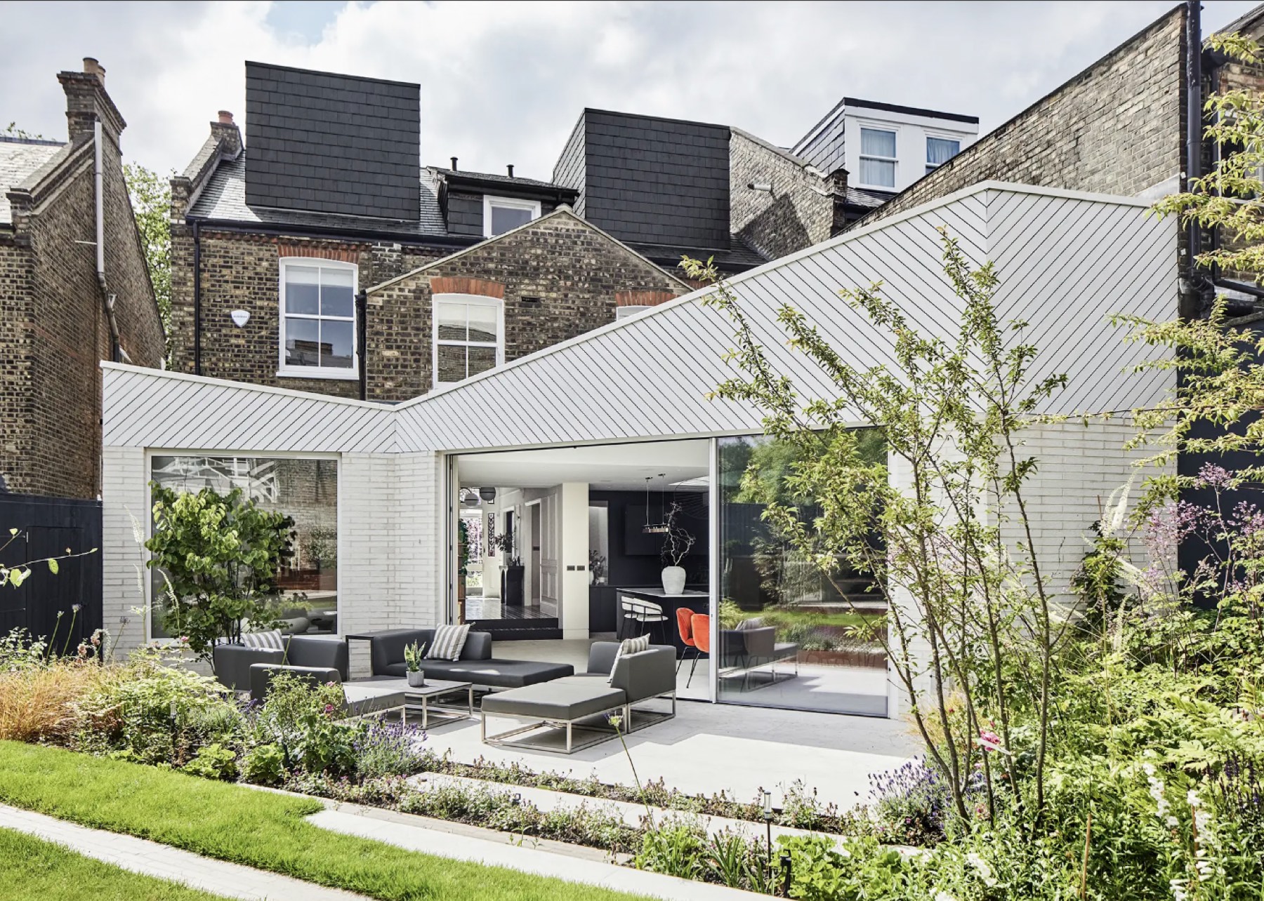 Zinc-clad rear extension with sliding glazing onto a planted garden
